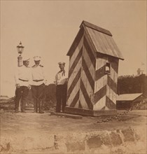 By the railway, three men in uniform standing near a guard booth, Vladivostok, Russia, 1899. Creator: Eleanor Lord Pray.