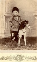 Portrait of a boy sitting on a toy horse, late 19th cent - early 20th cent. Creator: Unknown.