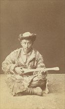 Kazakh man, a musician with a dombra, seated, between 1870 and 1886. Creator: Unknown.