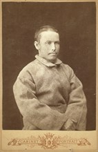Half-length portrait of a man in convict coat, seated, facing right, between 1880 and 1886. Creator: Unknown.