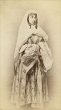 Full-length portrait of a woman, facing slightly right, in traditional dress, between 1870 and 1886. Creator: Unknown.