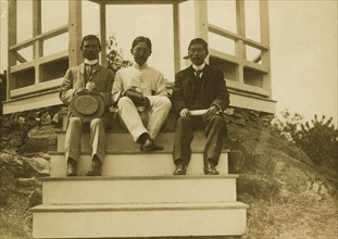 Three Japanese men, possibly journalists, seated on the steps of a gazebo, 1905. Creator: Unknown.