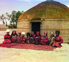 Group of eleven adults and children, seated on a rug, in front of a yurt, between 1905 and 1915. Creator: Sergey Mikhaylovich Prokudin-Gorsky.