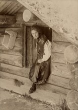 Girl looks out from a doorway, 1890-1920. Creator: Helene Edlund.