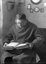 An elderly man sits and reads a book, 1880-1910. Creator: Johan Severin Nilson.