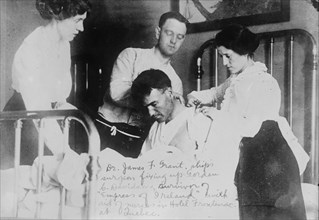 Dr. James F. Grant, ship's surgeon, fixing up Gordon G. Davidson, survivor of EMPRESS OF..., 1914. Creator: Bain News Service.