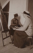 Maud Sherwood painting a dutchman with a clay pipe, 1913. Creator: Unknown.