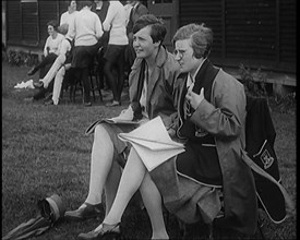 Two Female Civilians Wearing School Uniforms Taking Notes on a Notepad on the Side of a..., 1920. Creator: British Pathe Ltd.