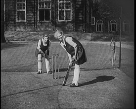 Two Female Civilians Wearing Gymslips and Batting Pads Preparing to Bat in a Playing Field, 1920. Creator: British Pathe Ltd.