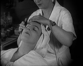 Female Civilian Having Her Face Massaged by Another Female Civilian Wearing an Electric, ... 1920. Creator: British Pathe Ltd.