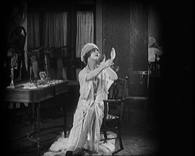 Female Civilian Seating in Front of a Dressing Table Wearing a Nightgown and Boudoir Cap..., 1920. Creator: British Pathe Ltd.