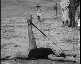 Female Civilian Laying on the Sand Exercising with an Elastic Band on a Beach, 1920. Creator: British Pathe Ltd.