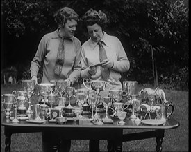 Two Female Civilians Standing Behind a Table Loaded with Trophies, 1920. Creator: British Pathe Ltd.