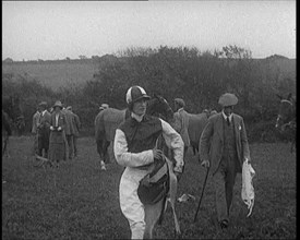 A Female Civilian Wearing a Jockey's Outfit Walking on a Horse Racing Track Watched by a..., 1920. Creator: British Pathe Ltd.