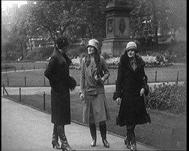 Three Female Civilians Wearing Glamorous Outfits and Long Boots Walking on a Park, 1920. Creator: British Pathe Ltd.
