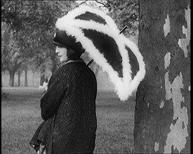 Female Civilian Dressed Glamorously Holding a Fur Trimmed Parasol in a Park, 1920. Creator: British Pathe Ltd.