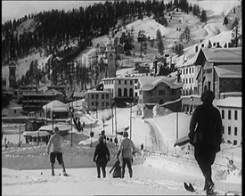 A Group of Female Civilians Skiing down a Snowy Hill with a Picturesque Alpine Village..., 1920. Creator: British Pathe Ltd.
