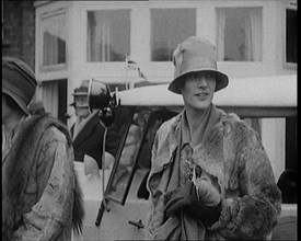 Two Female Civilians Wearing Heavy Coats and Hats Standing in Front of a Car, 1920. Creator: British Pathe Ltd.