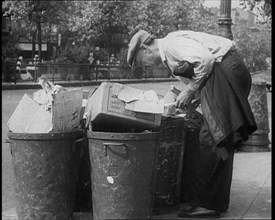 Male American Civilian Hunting Through a Rubbish Bin, 1930. Creator: British Pathe Ltd.