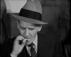 Male American Civilian Smoking a Cigarette While Reporting from the Courtroom During the..., 1930s. Creator: British Pathe Ltd.