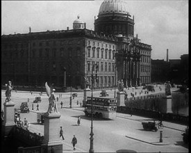 Bus Driving Down a Wide Road with a Large Building in the Background, 1933. Creator: British Pathe Ltd.