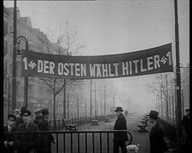 Men Walking Below Banner Reading: '1 Der Osten Wahlt Hitler 1' , 1933. Creator: British Pathe Ltd.