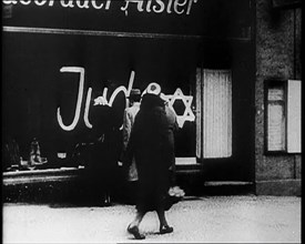 Civilians Looking at  Shop Window with Graffiti Reading: ‘Juden’ on it, 1933. Creator: British Pathe Ltd.