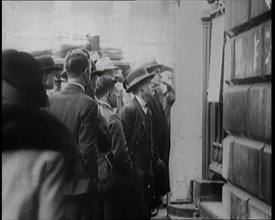 A Group of Male Civilians Looking at a Poster Attached to a Gate, 1926. Creator: British Pathe Ltd.