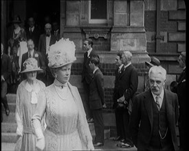 Queen Mary and King George V Accompanied by a Group of Officials Emerging from a Building , 1924. Creator: British Pathe Ltd.