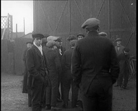 Male Civilian in a Flat Cap Facing a Wall. Another Male Civilian Carries a Sack Over His..., 1924. Creator: British Pathe Ltd.