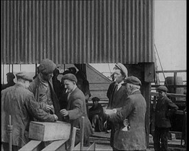 A Group of Miners Gathering and Smoking at a Pit Head, 1920. Creator: British Pathe Ltd.