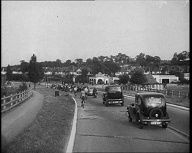 Cars and Bikes Driving Down a Road Away from the Camera, 1930s. Creator: British Pathe Ltd.