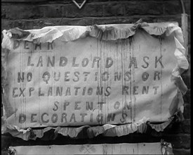 Poster Hanging on Wall Reading 'DEAR LANDLORD ASK NO QUESTIONS OR EXPLANATIONS RENT SPENT..., 1937. Creator: British Pathe Ltd.