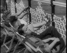 A Woman Sleeping in a Deckchair by Railings on the Promenade at Brighton With a Man and..., 1939. Creator: British Pathe Ltd.