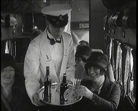 A Male Waiter Serves Smiling and Laughing Passengers Drinks  Inside an Aircraft, 1920s. Creator: British Pathe Ltd.