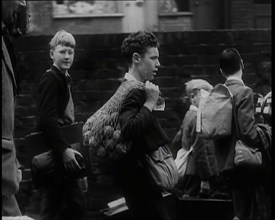 A Small Group of British Male Evacuees Carrying Bags and Walking Next to a Brick Wall, 1939. Creator: British Pathe Ltd.