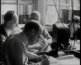 Four Male British Journalists Sitting Around a Table Covered in Papers and Writing, 1939. Creator: British Pathe Ltd.