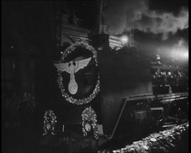 A Steam Train Decorated With Nazi Insignia on the Front Pulls Into a Station at Night, 1937. Creator: British Pathe Ltd.