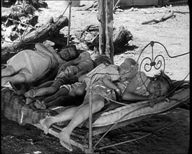 Barefoot Female Children Sleeping On a Bedframe Outside, 1932. Creator: British Pathe Ltd.