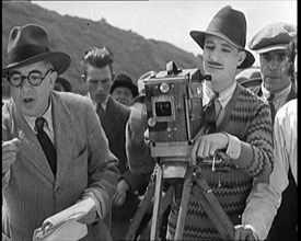 A Male Cameraman Cranking a Camera On a Film Set as the Male Director Instructs Actors, 1920s. Creator: British Pathe Ltd.