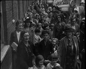 British Women and Child Evacuees Walking Along the Pavement of a Residential Street Next..., 1939. Creator: British Pathe Ltd.