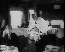 Passengers Sitting in the Dining Car of a Train as They Are Waited on by Attendants, 1938. Creator: British Pathe Ltd.