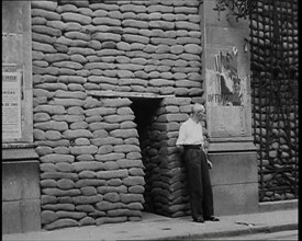 A Man Standing Outside the Frontage of a Building Obscured By Sandbags Next To an..., 1937. Creator: British Pathe Ltd.