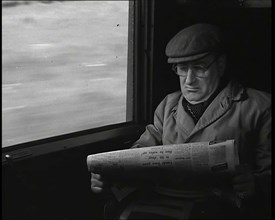 A Man in a Flat Cap and Spectacles Reading a Folded Newspaper in the Window Seat of a Train..., 1938 Creator: British Pathe Ltd.