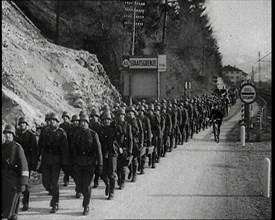 A Line of Male German Soldiers Marching Through a Customs Point Alongside a High Bank..., 1938. Creator: British Pathe Ltd.