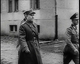 A Male Polish Army Commander Walking Past the Corner of a Large Building With Two Male... 1939. Creator: British Pathe Ltd.