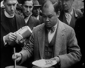 Man Serving Meals For Group of People from the Street Kitchen, 1932. Creator: British Pathe Ltd.