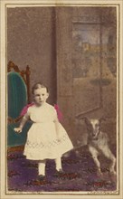 Unidentified little girl standing with a dog on the floor next to her, 1865-1875. Creator: Bent.