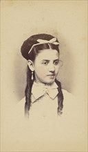 Unidentified young woman with two long curls, wearing a white bow in hair, 1870-1875. Creator: C.L. Lochman.