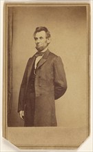 Abraham Lincoln standing with one arm behind his back, about 1864. Creator: Studio of Mathew B. Brady.